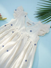 गैलरी व्यूवर में इमेज लोड करें, A zoomed in view of a handwoven cotton wrap dress with black dotted design, a baby girl's dress on a light bluish background.