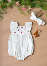Load image into Gallery viewer, A white baby girl dress with head band and a cute little deer-friend is kept on a light peach background with some flowers aside.
