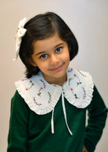 Load image into Gallery viewer, A young kid wearing the white combo of detachable victorian style collar and matching bow with subtle hand embroidery upon dark green top standing in front of a white background.