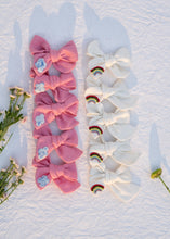 Load image into Gallery viewer, Several bows, pink and off-white, laying in a white background, all with flowers and leaves