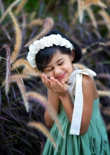 Load image into Gallery viewer, A girl posing by wearing ruffled white headband near a plant.