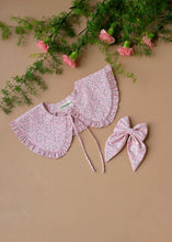 Load image into Gallery viewer, A beautiful pink floral combo of detachable victorian style collar and matching bow with small frills around it for kids kept on light peach background with some flowers aside.
