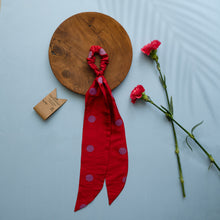 गैलरी व्यूवर में इमेज लोड करें, A beautiful red silk hair scrunchie kept upon a round wooden log with some flowers and brown card aside.