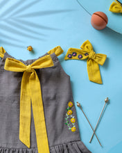 गैलरी व्यूवर में इमेज लोड करें, A beautiful dress with extra-long bow tie strap with a matching hair accessory kept on a blue floor with some leaf, flower and needle aside.