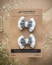 Load image into Gallery viewer, A pair of mini black and white hair accessory tied on a brown card with some flowers in the background.
