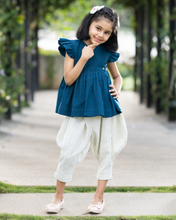 गैलरी व्यूवर में इमेज लोड करें, A young girl posing by wearing elegant blue flutter sleeve top and cream balloon pant with blur background.