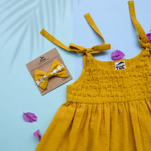 Load image into Gallery viewer, A beautiful adjustable shoulder strap dress with matching hair accessory kept upon a blue background with some leaf petals aside.