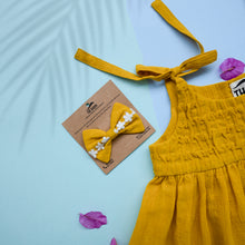 Load image into Gallery viewer, A beautiful adjustable shoulder strap dress with matching hair accessory kept upon a blue background with some leaf petals aside.