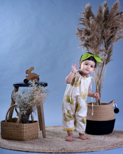 गैलरी व्यूवर में इमेज लोड करें, A baby girl wearing a jumpsuit with matching hair accessories with some artificial plants and wooden pots and with some rabbit toys and a flower basket aside.