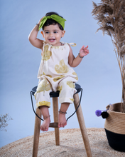 गैलरी व्यूवर में इमेज लोड करें, A baby girl wearing a jumpsuit with matching hair accessories sitting on a chair with some artificial plant aside.