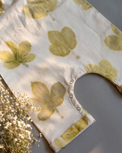 गैलरी व्यूवर में इमेज लोड करें, A cute baby girl dress made of eco-printed Indian maple leaves on it along with some flower aside.