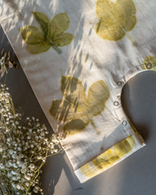 गैलरी व्यूवर में इमेज लोड करें, A cute baby girl dress made of eco-printed Indian maple leaves on it along with some flower aside.