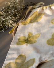 गैलरी व्यूवर में इमेज लोड करें, A cute baby girl dress made of eco-printed Indian maple leaves on it along with some flower aside.