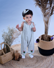 गैलरी व्यूवर में इमेज लोड करें, A baby girl wearing cute jumpsuit with matching hair accessories with some artificial plants and wooden pots and with some rabbit toys and a flower basket aside.