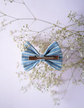 Load image into Gallery viewer, A rear view of the blue and white designed lace bow hair accessory with a clip, on a serene background.
