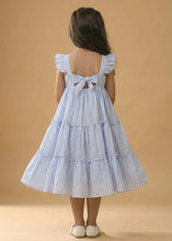 Load image into Gallery viewer, Child wearing a blue and white striped dress with a ruffled back on a beige background
