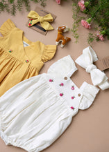Load image into Gallery viewer, A beautiful pair of organic cotton baby clothes and a pair of hair accessories with a cute toy beside it kept on a light peach background with some flower aside.
