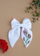Load image into Gallery viewer, A Red Embroidered White Hairclip for kids hair accessories placed on a light brown background with flowers and leaves as decor
