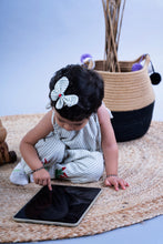 Load image into Gallery viewer, A baby girl wearing a cute butterfly accessory sitting on a jute mate and using tablet.
