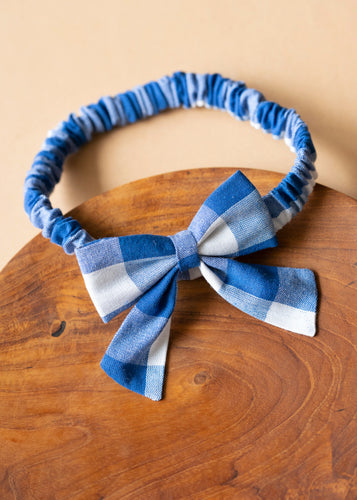 A beautiful cotton handmade blue headbanded bow for kidswear kept upon a wood.