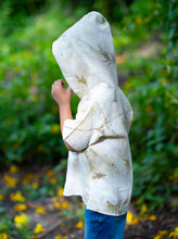 गैलरी व्यूवर में इमेज लोड करें, A kid posing in the middle of the street wearing a unisex hooded kurta eco-printed using silver oak leaves.
