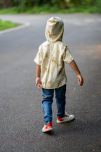 गैलरी व्यूवर में इमेज लोड करें, A kid walking in the middle of the street wearing a unisex hooded kurta eco-printed using silver oak leaves.
