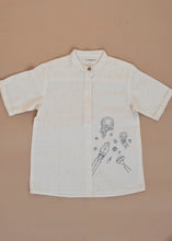 Load image into Gallery viewer, A white coloured Organic Cotton Doodle Shirt kidswear with space theme design kept on a biege coloured background
