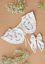 Load image into Gallery viewer, A beautiful combo of detachable victorian style collar and matching bow with subtle hand embroidery for kids kept on light peach background with some flowers aside.
