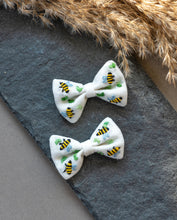 Load image into Gallery viewer, A pair of beautiful honeybee hair accessories  kept on gray cloth with brown feathers aside.
