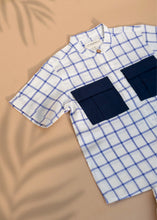 Load image into Gallery viewer, A unisex organic cotton baby clothes Shirt with Patch Pocket with indigo checkmate design kept on a beige background
