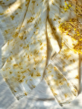 Load image into Gallery viewer, A beautiful muslin baby swaddle with marigold ecoprinted on it with some flowers aside.

