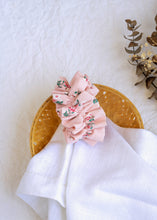 Load image into Gallery viewer, A hair accessory of Pink Floral Scrunchies placed in a wooden basket with a white cloth beneath, placed on a white background with some leaves and decoratives
