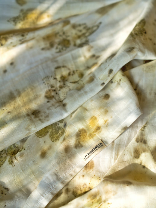 A beautiful muslin baby swaddle with rose leaves ecoprinted on it.