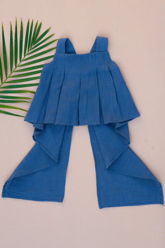 A beautiful Pure Cotton Indigo coloured Pleated Top for kidswear placed on a peach background with a leaf aside