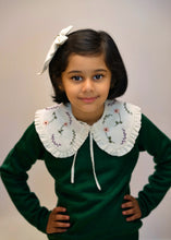 Load image into Gallery viewer, A young kid wearing the white combo of detachable victorian style collar and matching bow with subtle hand embroidery upon dark green top standing in front of a white background.
