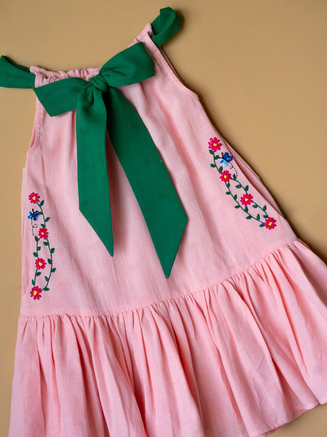 A beautiful dress with extra-long bow tie strap kept on a floor.