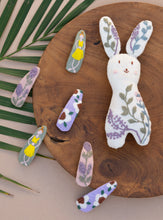 Load image into Gallery viewer, Collection of Linen Tic Tac Embroidery Hair Clips in pastel colors lying on a wooden tray beside a rabbit shaped toy.

