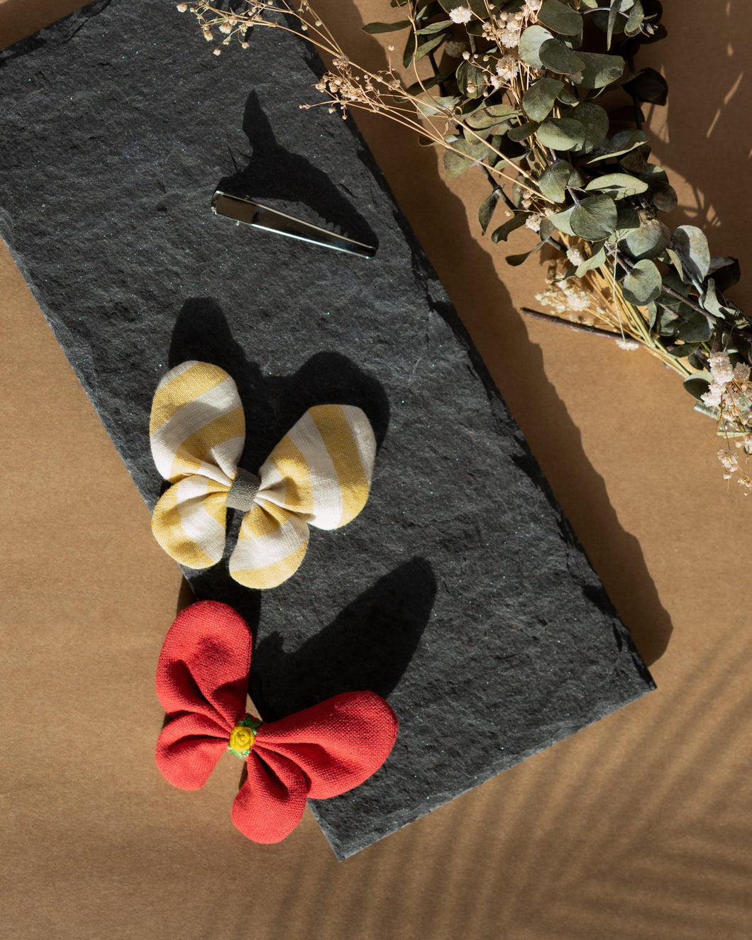 A very cute and beautiful butterfly combo hair accessories placed upon a grey sheet with some leaves aside.