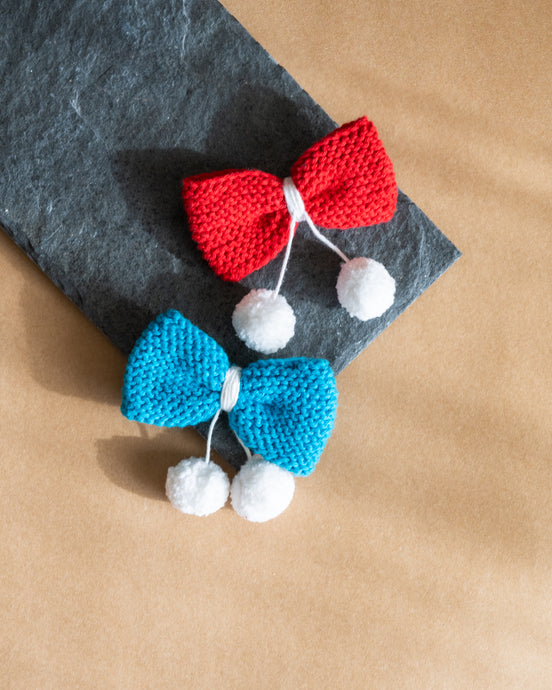 A beautiful, knitted blue and red head bow hair accessories kept on grey sheet.