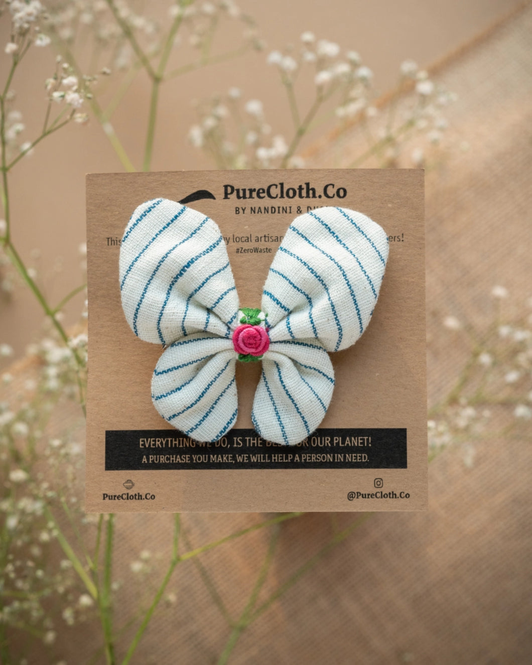 A cute butterfly hair accessories tied on a brown card placed upon a flower.