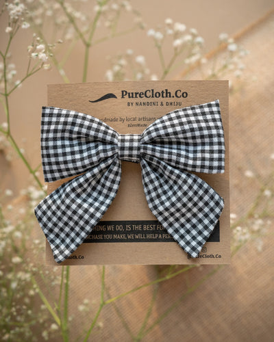 An organic cotton handmade bow hair accessory for kidswear tied upon a brown card.