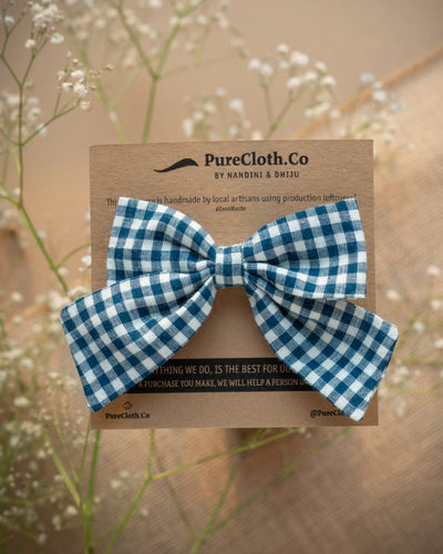 An organic cotton handmade bow hair accessory for kidswear tied upon a brown card.
