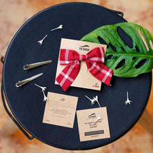 Load image into Gallery viewer, An organic cotton handmade bow hair accessories for kids tied upon a brown card Placed upon a dark blue plate with some leaves aside.
