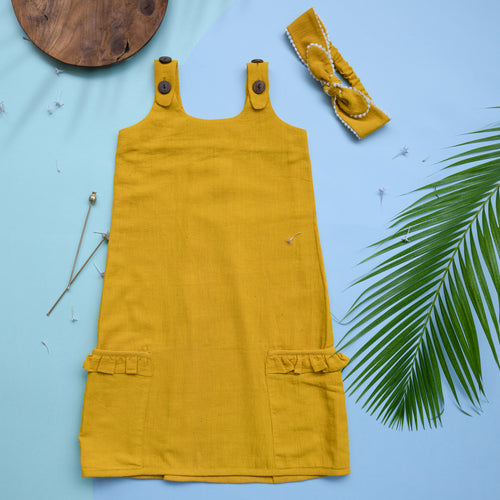 A beautiful deep yellow extendable shift dress with matching hair accessory with wooden, two bi needles and leaf aside.
