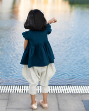 गैलरी व्यूवर में इमेज लोड करें, A young girl pointing towards swimming pool by wearing elegant blue flutter sleeve top and cream balloon pant with blur background.
