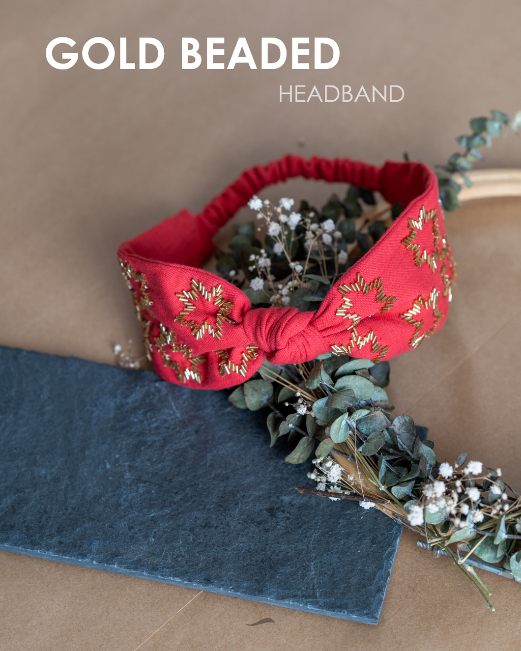 A beautiful gold-beads hand crafted on red cotton fabric hair accessories kept on a dried leaf tiara with some gray sheet under it.