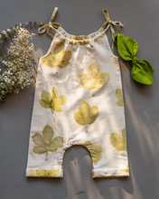 गैलरी व्यूवर में इमेज लोड करें, A cute baby girl dress made of eco-printed Indian maple leaves on it along with matching hair accessory and some flower aside.
