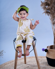 Load image into Gallery viewer, A baby girl wearing a jumpsuit with matching hair accessories sitting on a chair with some artificial plant aside.
