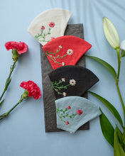 Load image into Gallery viewer, A different color organic cotton hand-embroidered adjustable face masks kept upon a grey sheet with some flowers aside.
