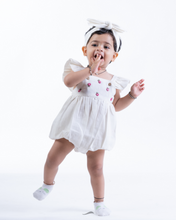 Load image into Gallery viewer, A baby posing by wearing white romper with matching hair accessory.
